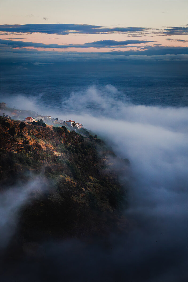 Hügel mit Häusern von Nebel umschlossen, im Hintergrund der Atlantik – stille Landschaftsimpression
